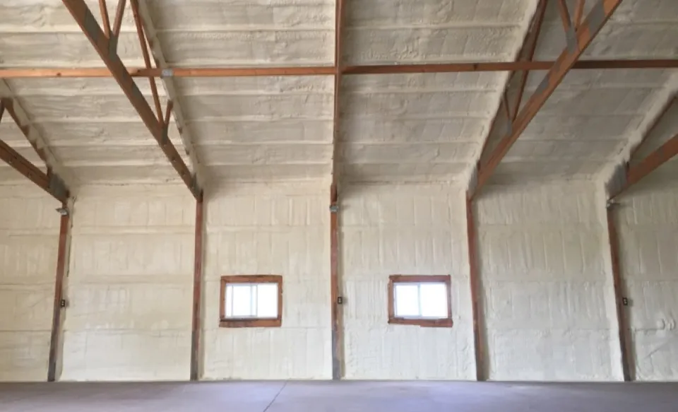 Open cell spray foam insulation applied to the roof and walls inside a timber-framed commercial building
